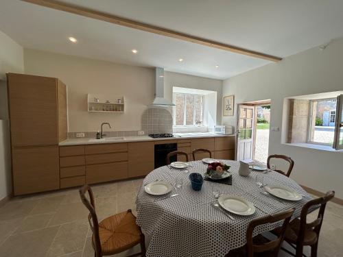 a dining room with a table and a kitchen at Maison Mélusine in Londigny