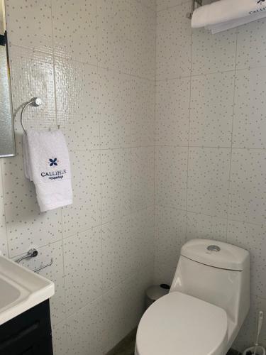 a bathroom with a white toilet and a sink at Refugio para 2 in Santa Cruz