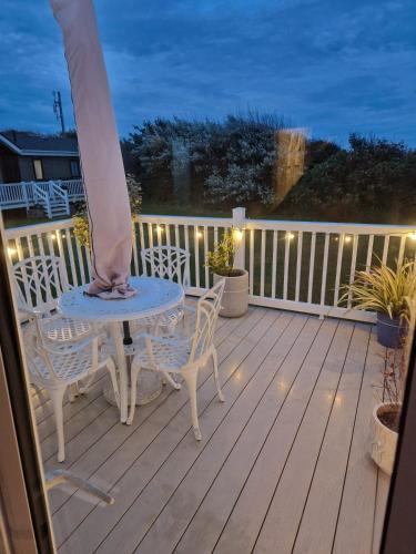 eine Veranda mit Tisch und Stühlen auf einer Terrasse bei Nacht in der Unterkunft Maise's in Camber