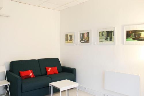 a living room with a green couch and red pillows at Souplex - 4P - Batignolles in Paris