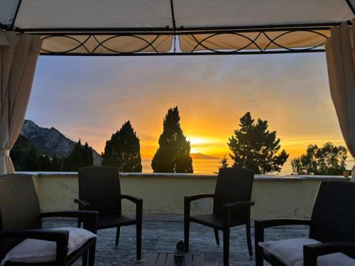 a view of a sunset from a balcony with chairs at Villa Aurora Caprese in Capri