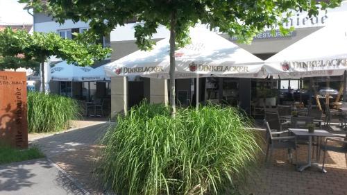 un restaurante con sillas, sombrillas y césped en Alte Schmiede en Großbottwar