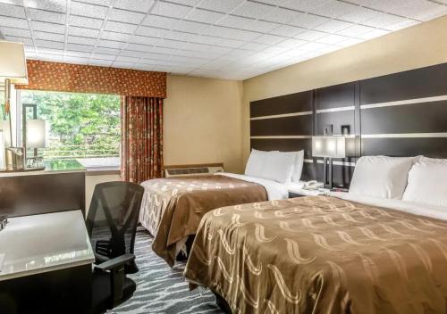 a hotel room with two beds and a desk and a window at Quality Inn East Stroudsburg - Poconos in East Stroudsburg