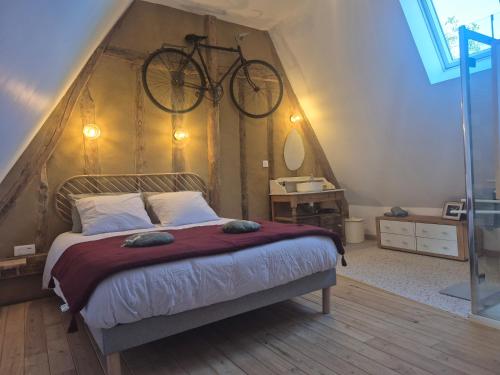 a bedroom with a bed with a bicycle on the wall at La Granch' - Maison d'hôtes in Harcourt