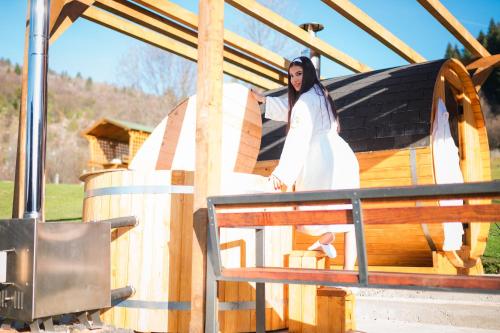 a woman standing next to a wooden house at Vikendica i odmaraliste JuliE, Sarajevo-Jahorina in Tvrdimići