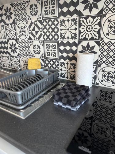 a kitchen counter with a black and white tile wall at Studio plage - Séjours pros et vacances in Dunkerque