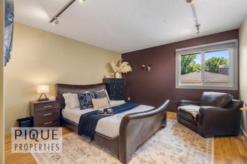 a bedroom with a bed and a chair and a window at Urban Oasis - with 16ft Swim Spa - Heated Hot Tub & Pool in Edmonton