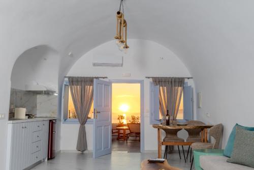 a kitchen and a living room with a table and a table at Sun Angelos Oia - Luxury Cave Suites in Oia