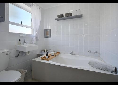 a white bathroom with a tub and a toilet at Skulpie in Cape Town