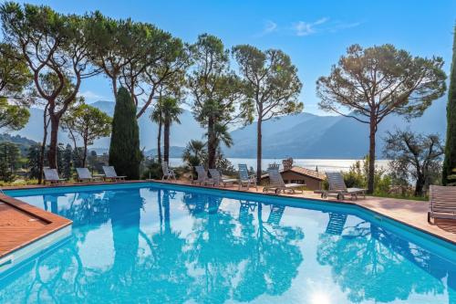 a swimming pool with chairs and mountains in the background at Brentano Elegante in Mezzegra