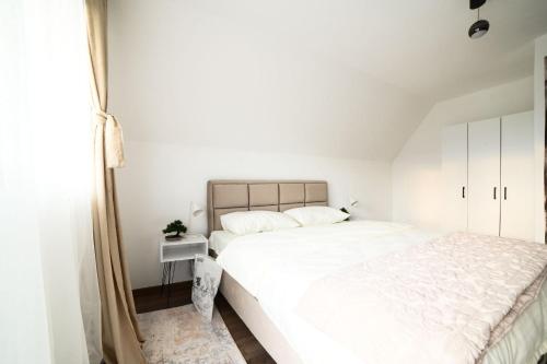 a bedroom with a large white bed and a window at Koala Resort in Raška
