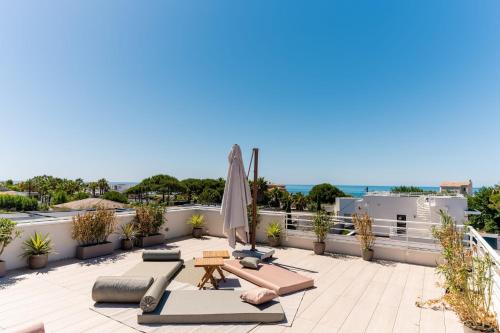 a rooftop patio with lounge chairs and an umbrella at Villa Maya Rooftop beach access heated pool in Le Grau-dʼAgde