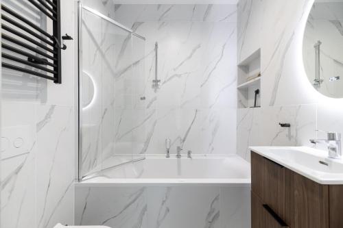 a white bathroom with a tub and a sink at Marina Dziwnow Premium Haus in Dziwnów