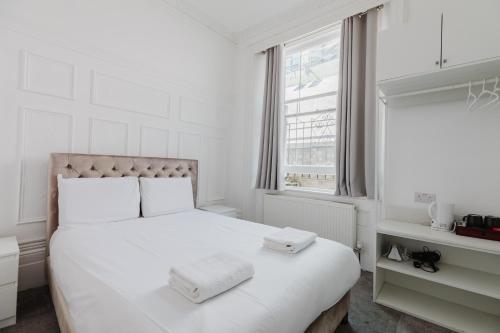 a white bedroom with a bed with two towels on it at The Hyde Hotel in London