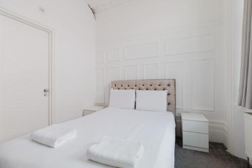 a white bedroom with a bed with white sheets and pillows at The Hyde Hotel in London