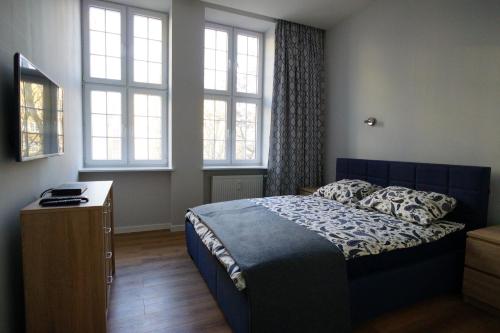 a bedroom with a bed and two windows at Apartament MARIACKA 42 in Gdańsk