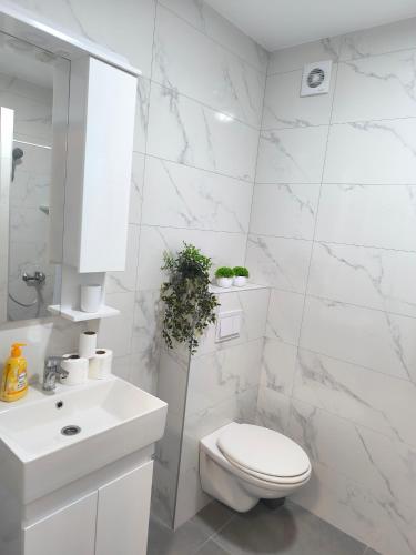 a white bathroom with a toilet and a sink at Tulipan LUX in Doboj