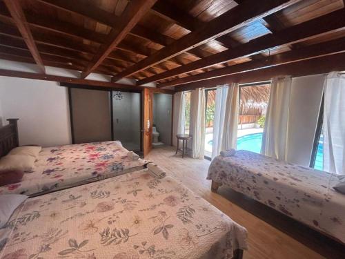 a bedroom with two beds and a large window at Liahs tortuguero in Tortuguero