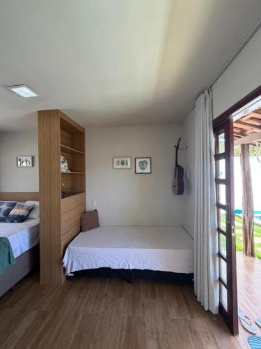 a bedroom with two beds and a sliding glass door at Chalé Brisa da Mata Baia Formosa in Baía Formosa