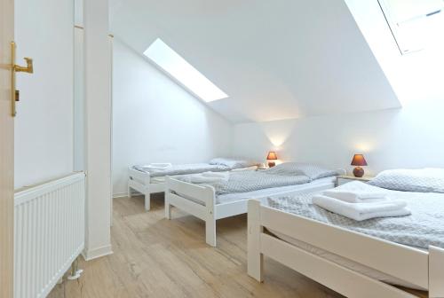 tres camas en una habitación con paredes blancas y suelos de madera. en Hotel Monaco, en Náměšť nad Oslavou