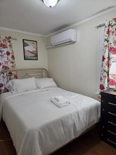 a bedroom with a bed with a white blanket at Stay by Gina in Irvington