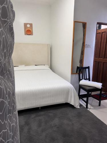 a bedroom with a white bed and a chair at Central Calm Apartment in Dar es Salaam