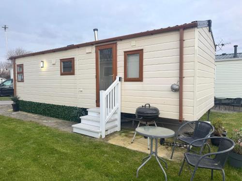 a tiny house with a grill and some chairs at Haighs caravan hire in Rhyl
