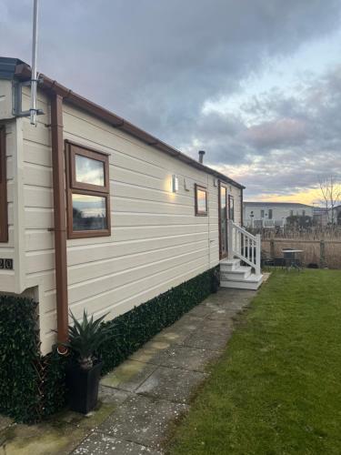 a white tiny house with a porch and a yard at Haighs caravan hire in Rhyl
