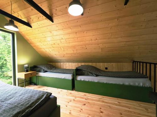 two beds in a room with wooden walls at Domek Daglezjowy in Małe Leżno