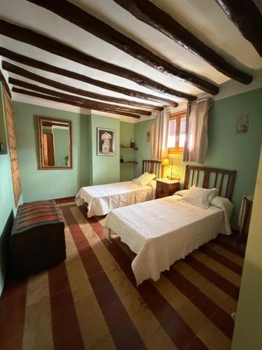 two beds in a room with green walls at Los Chinchanes in Santa Cruz de Grío
