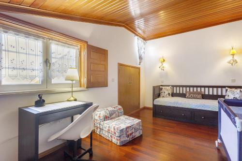 a living room with a bed and a desk and a chair at Sol Lua House in Fátima