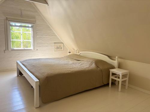 a white bedroom with a bed and a window at Hus Kråksmåla in Alsterbro