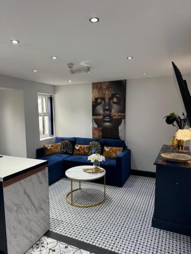 a living room with a blue couch and a table at Secret Garden Suite in Gloucestershire