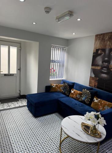 a living room with a blue couch and a table at Secret Garden Suite in Gloucestershire