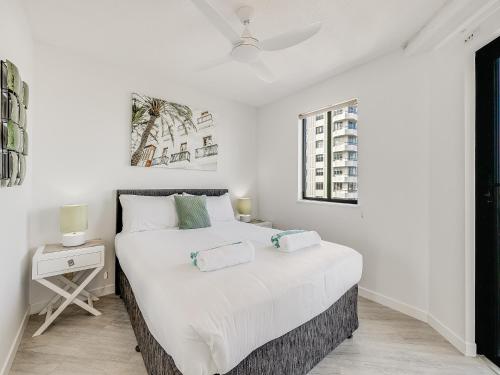 a white bedroom with a large bed and a window at Nautilus Private Rooftop Spa in Mooloolaba