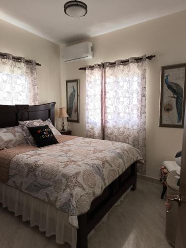 a bedroom with a large bed and two windows at Caribbean Luxury Penthouse in San Felipe de Puerto Plata