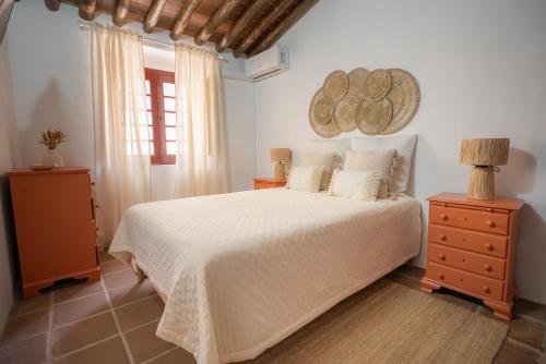 a bedroom with a white bed and a window at Horta dos Cismeiros, Monsaraz - Monte Alentejano com Piscina in Monsaraz
