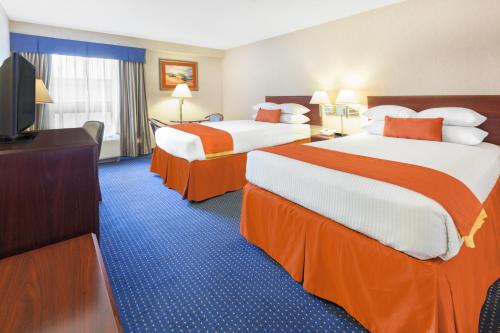 a hotel room with two beds and a flat screen tv at Wyndham Garden Monterrey Norte in Monterrey