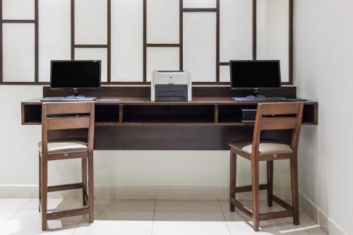 a desk with two computers and two chairs at Wyndham Garden Monterrey Norte in Monterrey