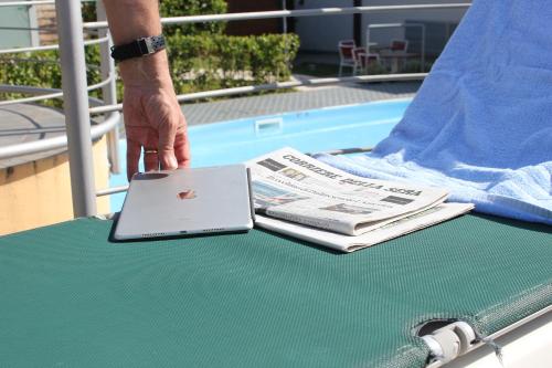 a person standing on a table with a laptop and a newspaper at Klass Hotel in Castelfidardo