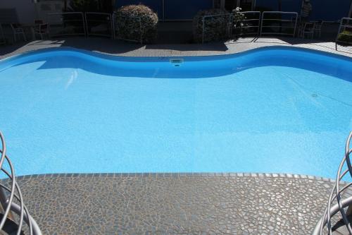 a large blue swimming pool with chairs around it at Klass Hotel in Castelfidardo