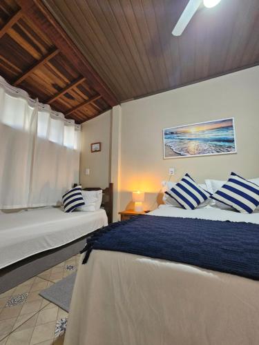 a bedroom with two beds with blue and white pillows at Flat Sol Paraty in Paraty