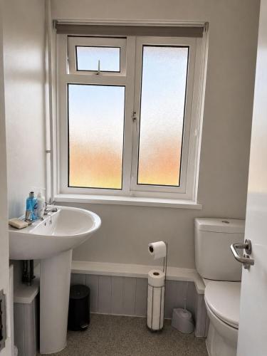 a bathroom with a sink and a toilet and a window at 3-Bedroom House ,Quiet & Spacious in Kent