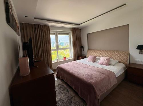 a bedroom with a large bed and a window at Vijolie West Exclusive in Warsaw
