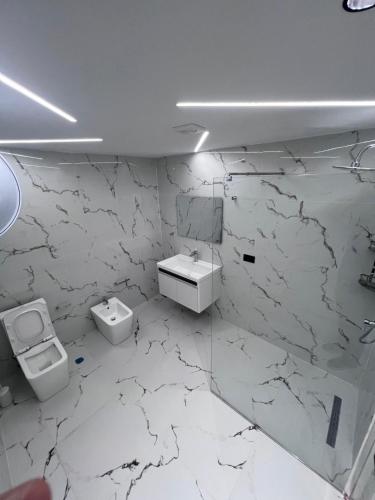 a white bathroom with a sink and a toilet at Ferra Hostel in Durrës