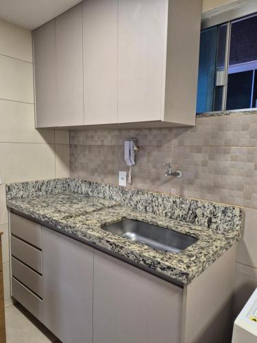 a kitchen with a sink and white cabinets at Apartamento automatizado valparaiso in Valparaíso de Goiás