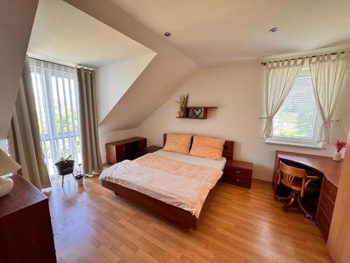 a bedroom with a bed and a desk and windows at Moravian Garden House Novosedly Adults Only in Novosedly