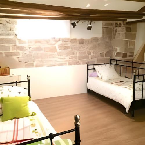 two beds in a room with a brick wall at Casita del Castillo Mora de Rubielos in Mora de Rubielos