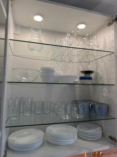 a shelf filled with glasses and plates in a kitchen at Apartament Lubię Błękit in Rowy