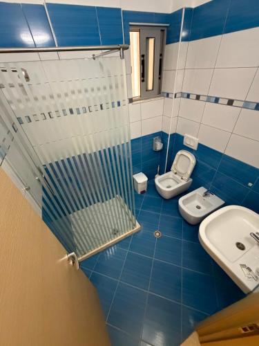 a blue and white bathroom with a shower and two toilets at Hotel Divers in Vlorë